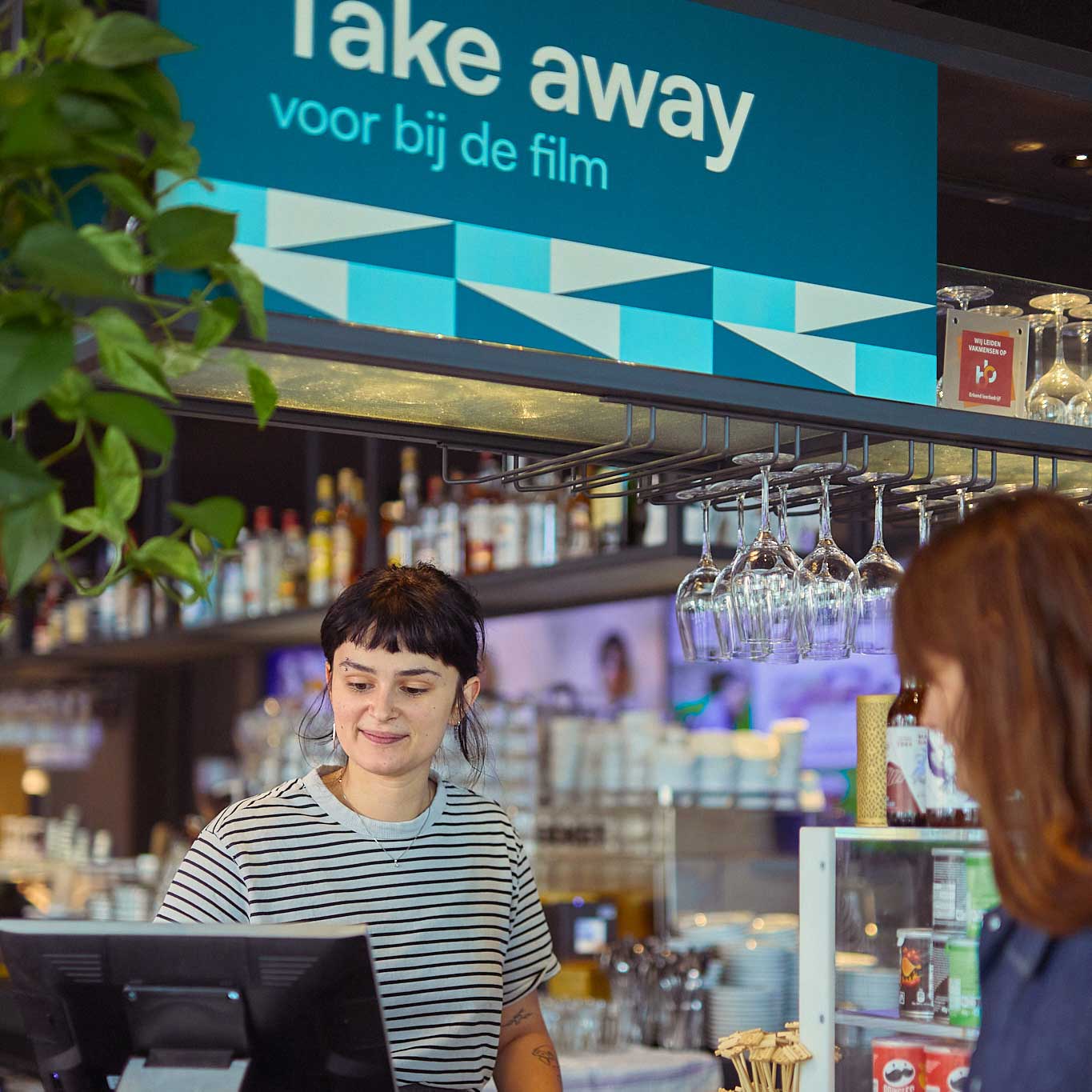 Vrouw achter kassa bij Take Away bord ontworpen door Diep Arnhem